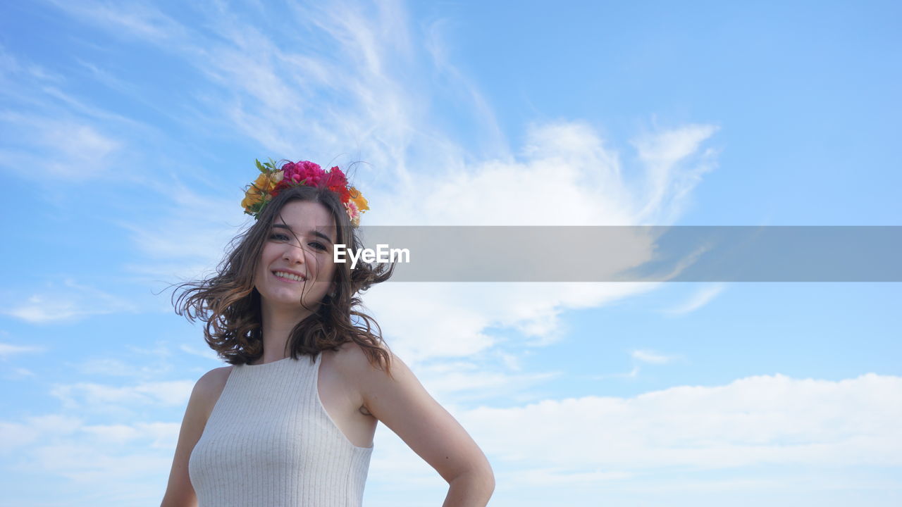 Portrait of a smiling young woman against sky