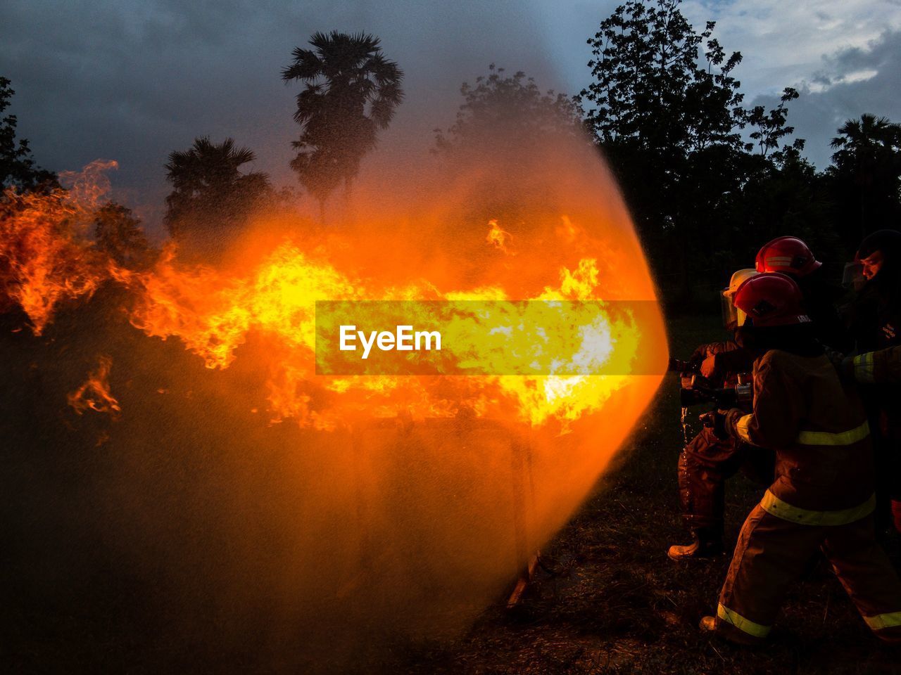 Fighters extinguishing fire on field at dusk 