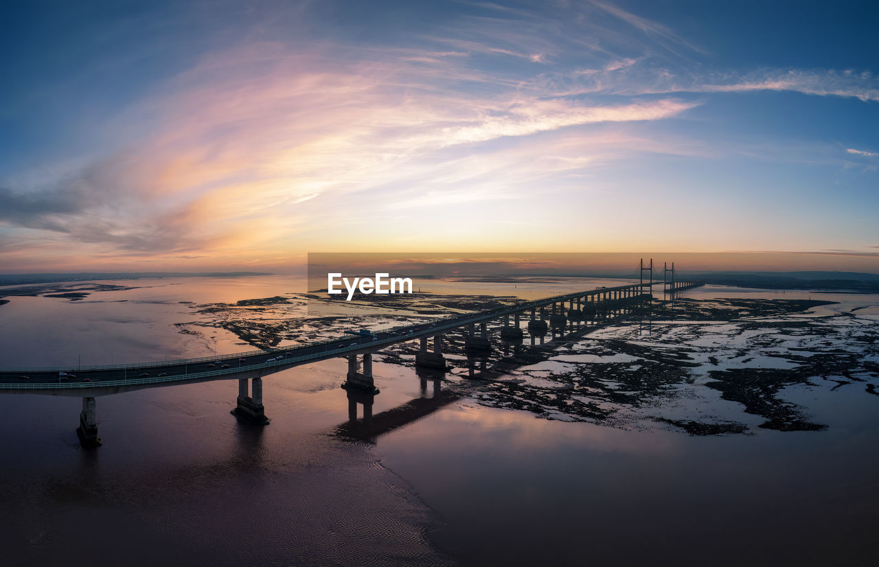 sky, reflection, water, dawn, sunrise, cloud, morning, horizon, nature, sunlight, scenics - nature, sea, beauty in nature, environment, landscape, snow, architecture, travel destinations, travel, tranquility, land, outdoors, cold temperature, sun, beach, tourism, blue, city, built structure, wave, dramatic sky, winter, tranquil scene, ocean, transportation, twilight, silhouette