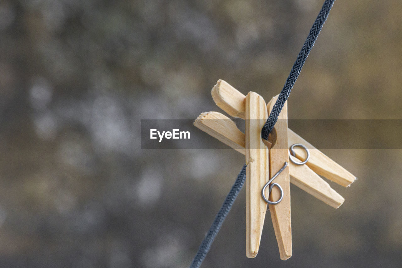 Two wooden clothespins on top of a blue clothesline in the blurr