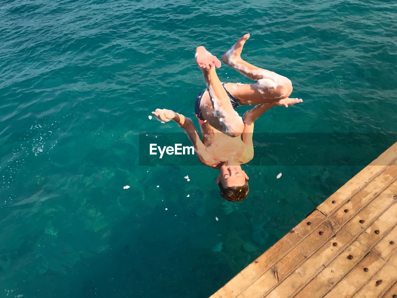 High angle view of boy jumping in sea
