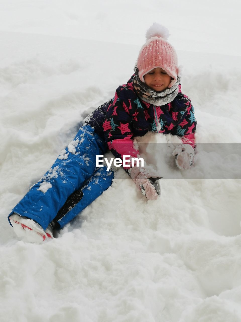 High angle view of girl sitting on snow covered field