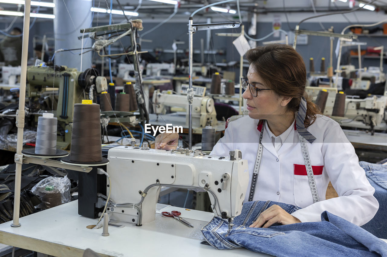 Working woman hands in textile factory sewing on industrial sewing machine. industrial production