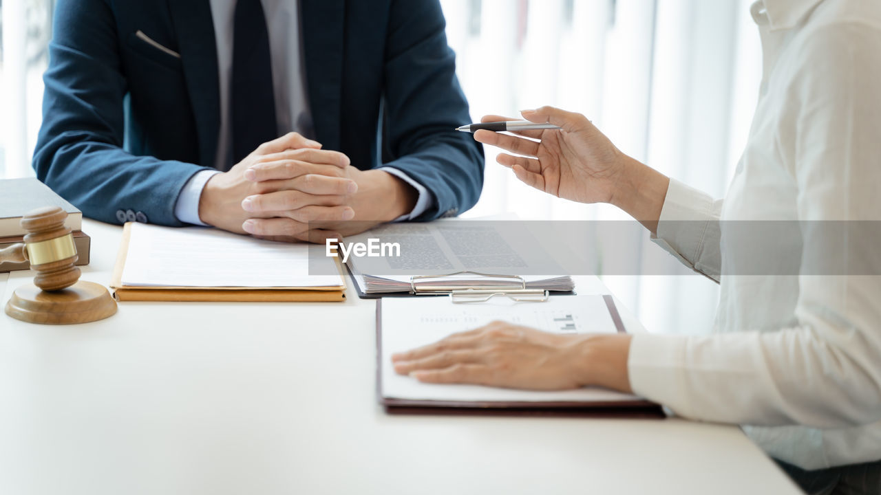 midsection of lawyer and client shaking hands in office