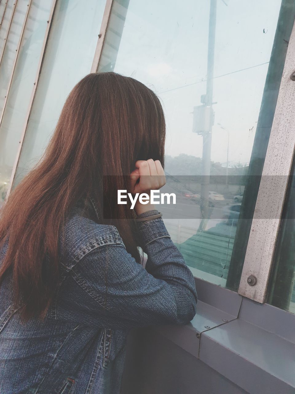 YOUNG WOMAN LOOKING THROUGH WINDOW AT GLASS