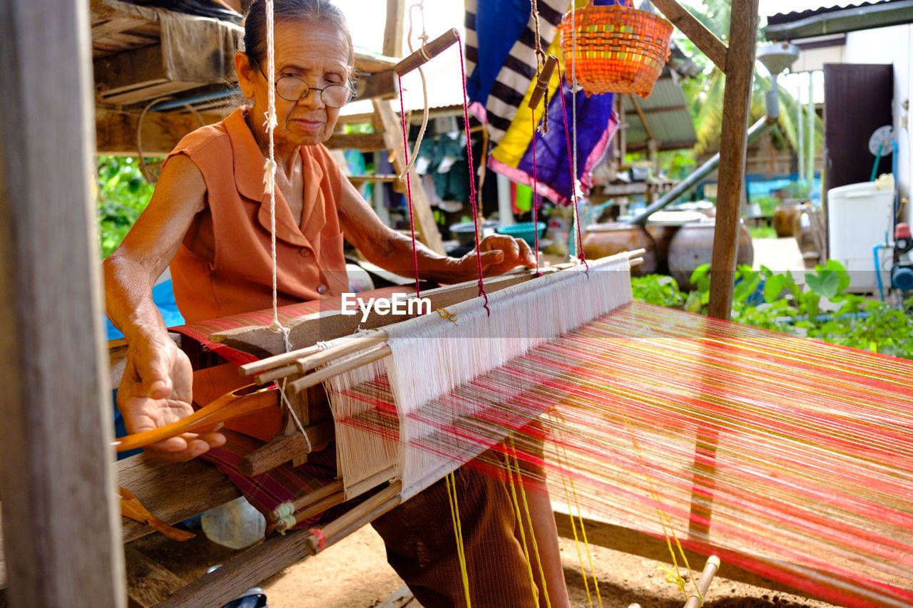 Close-up of senior woman weaving on equipment