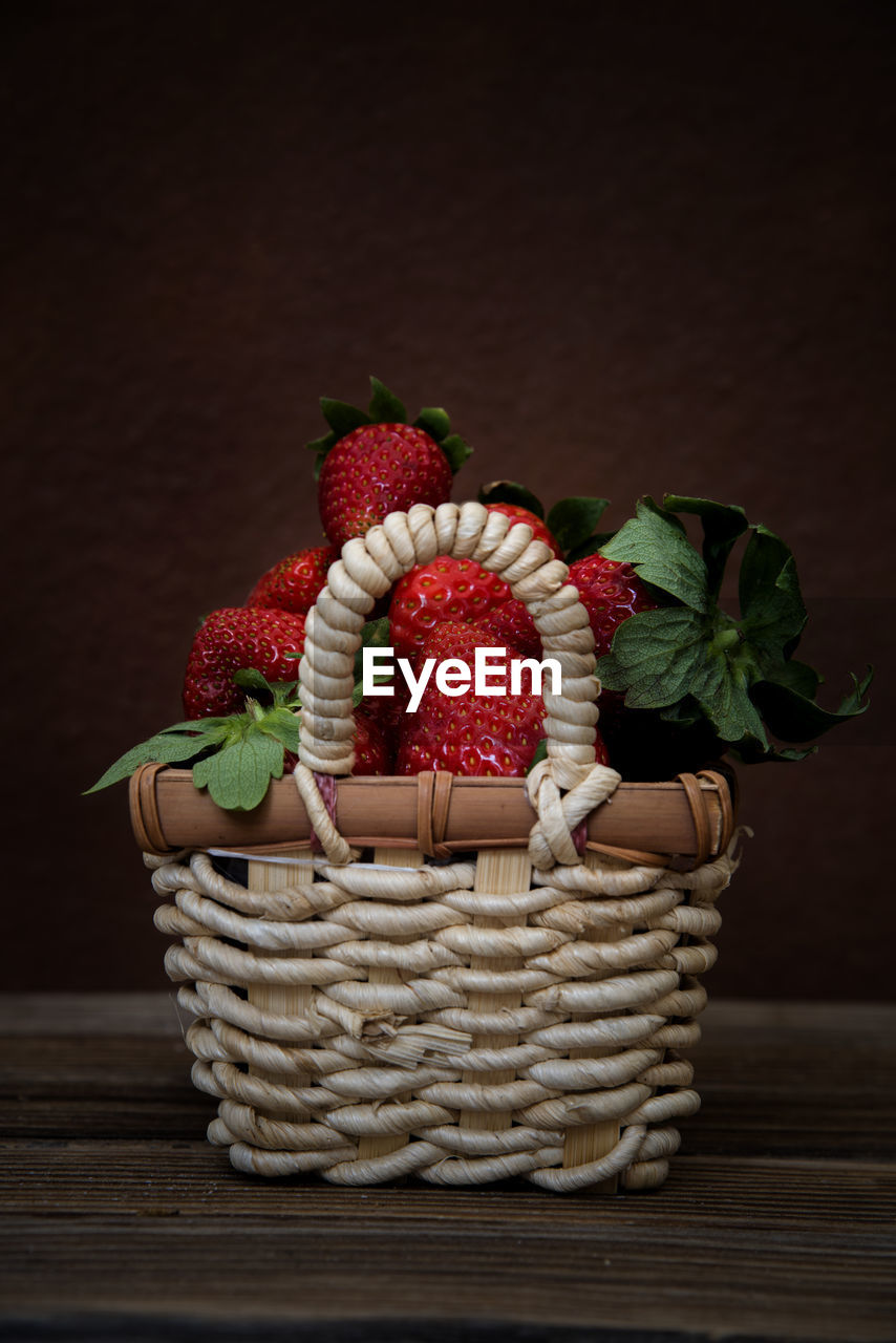 Small basket with strawberries on dark background