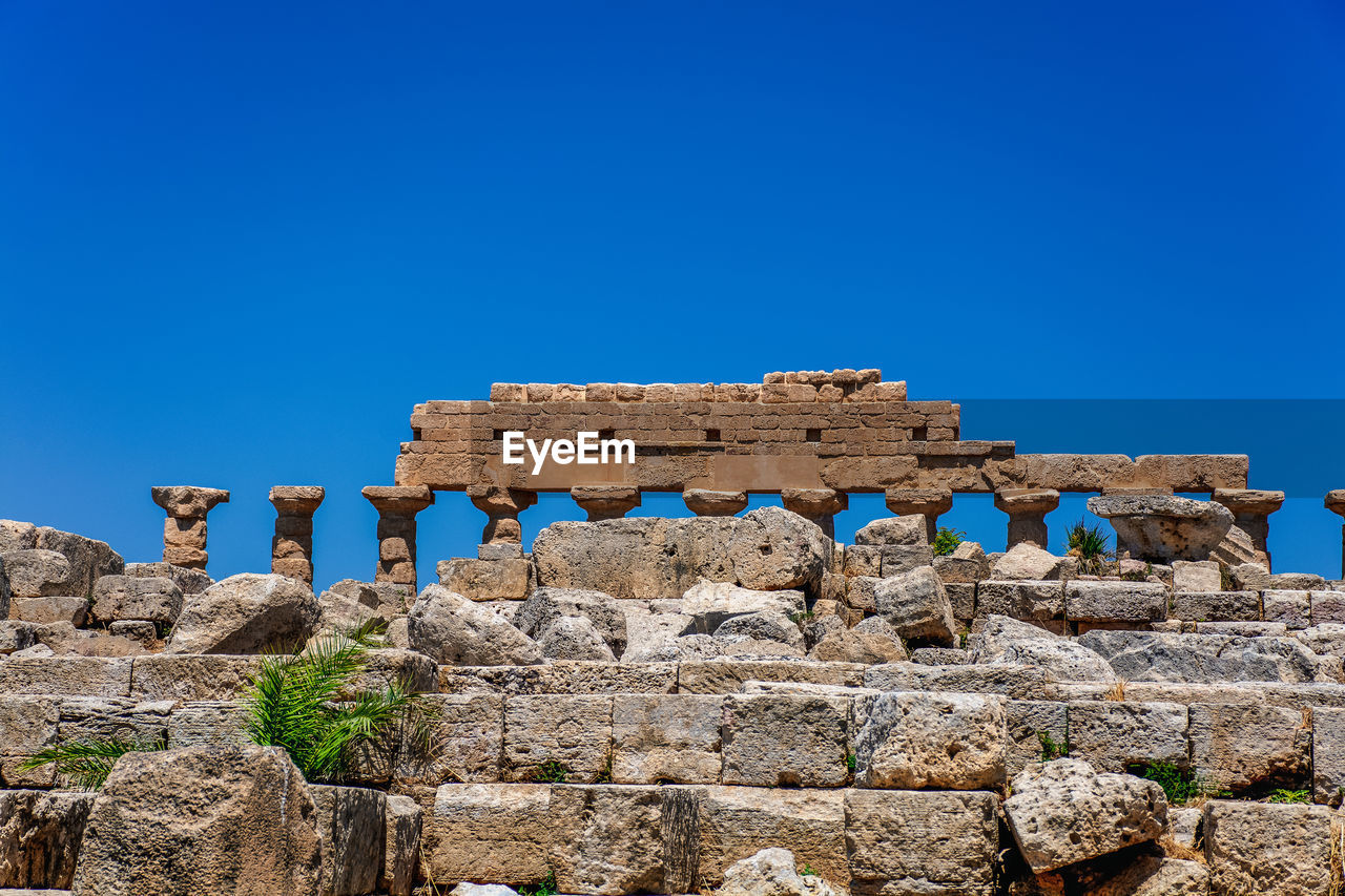 Low angle view of old ruins against clear blue sky