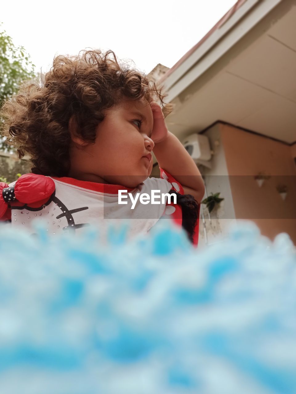 Low angle view of girl looking away standing by house