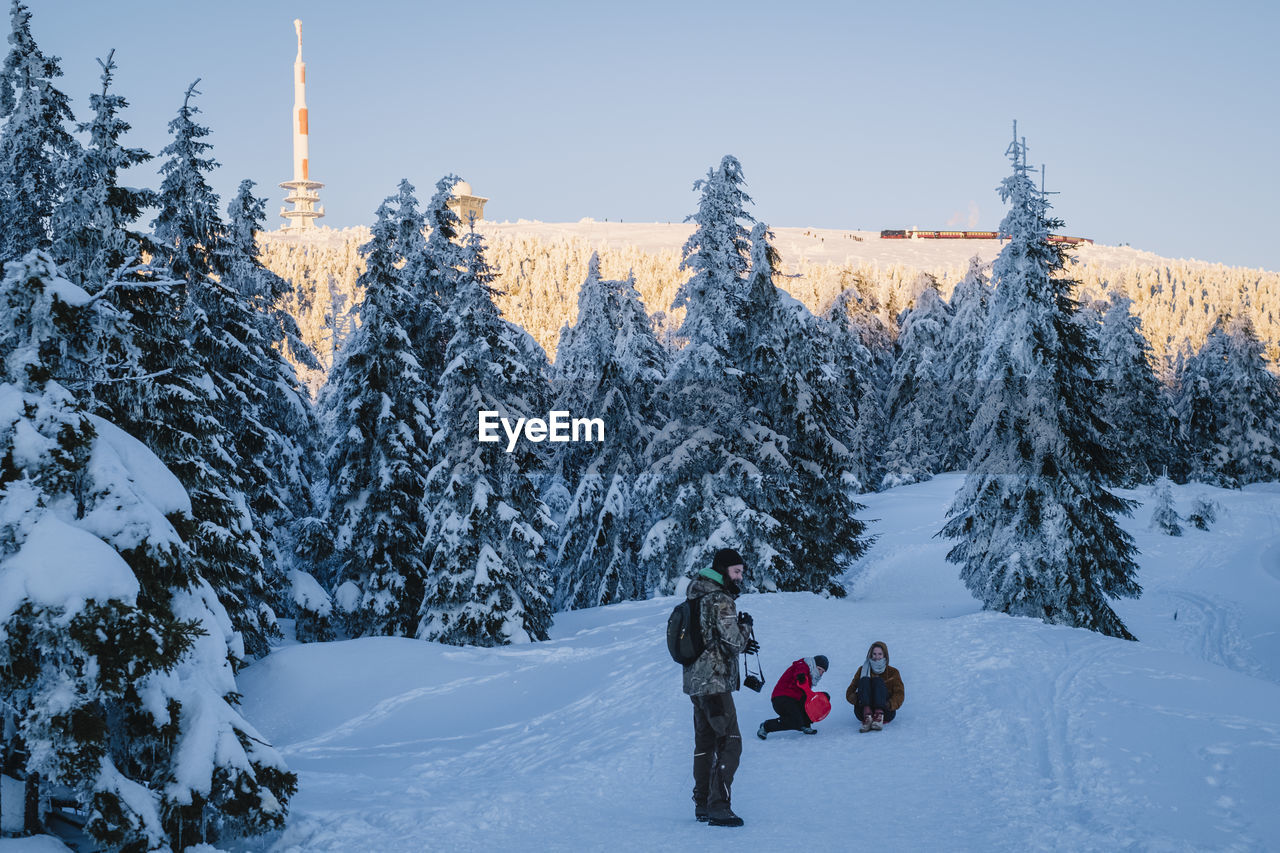 People on snow covered land against sky