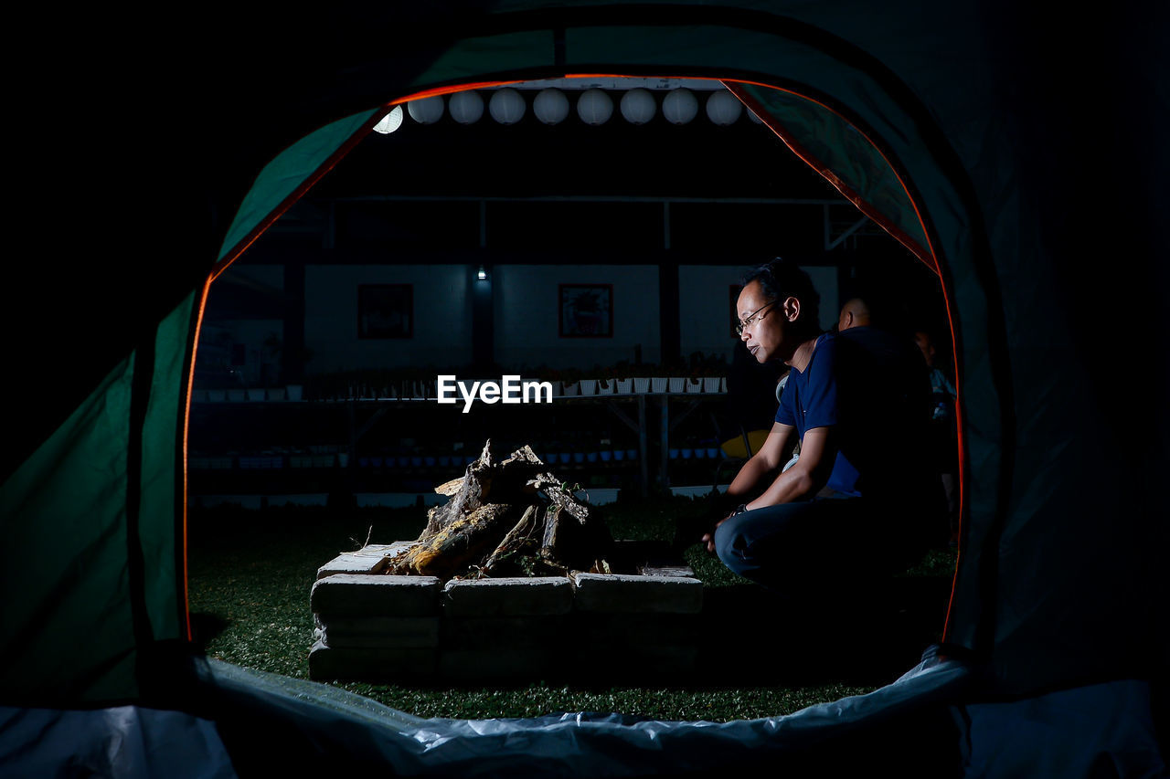 Rear view of man sitting in tent