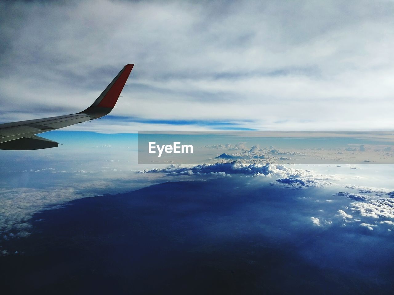 AERIAL VIEW OF SEA AND AIRPLANE WING AGAINST SKY