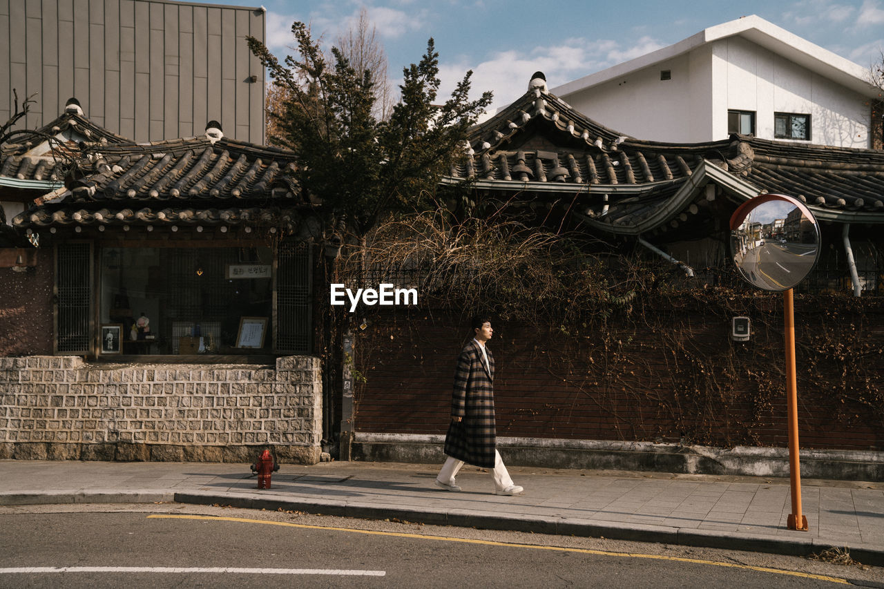 Man walking on sidewalk against buildings