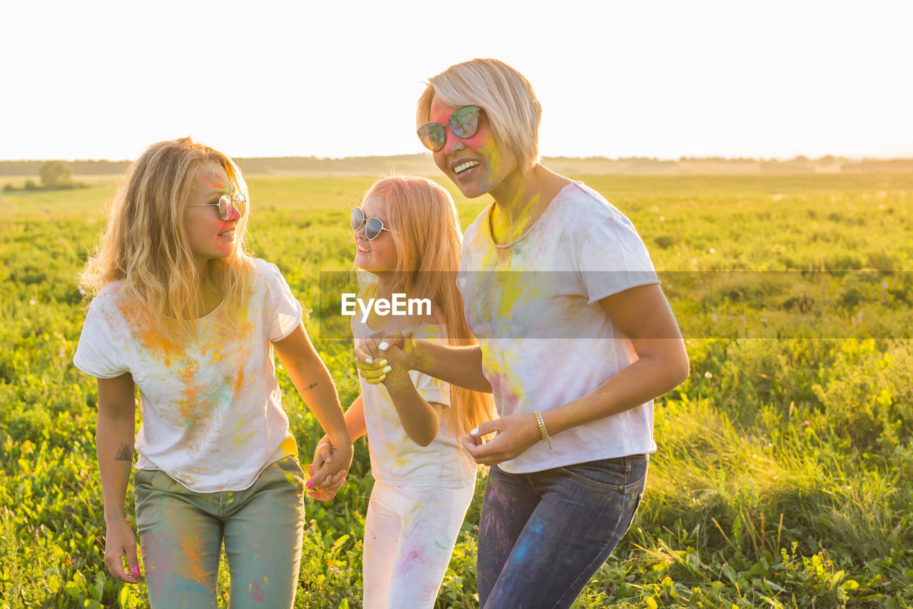 REAR VIEW OF WOMEN STANDING ON FIELD BY LAND