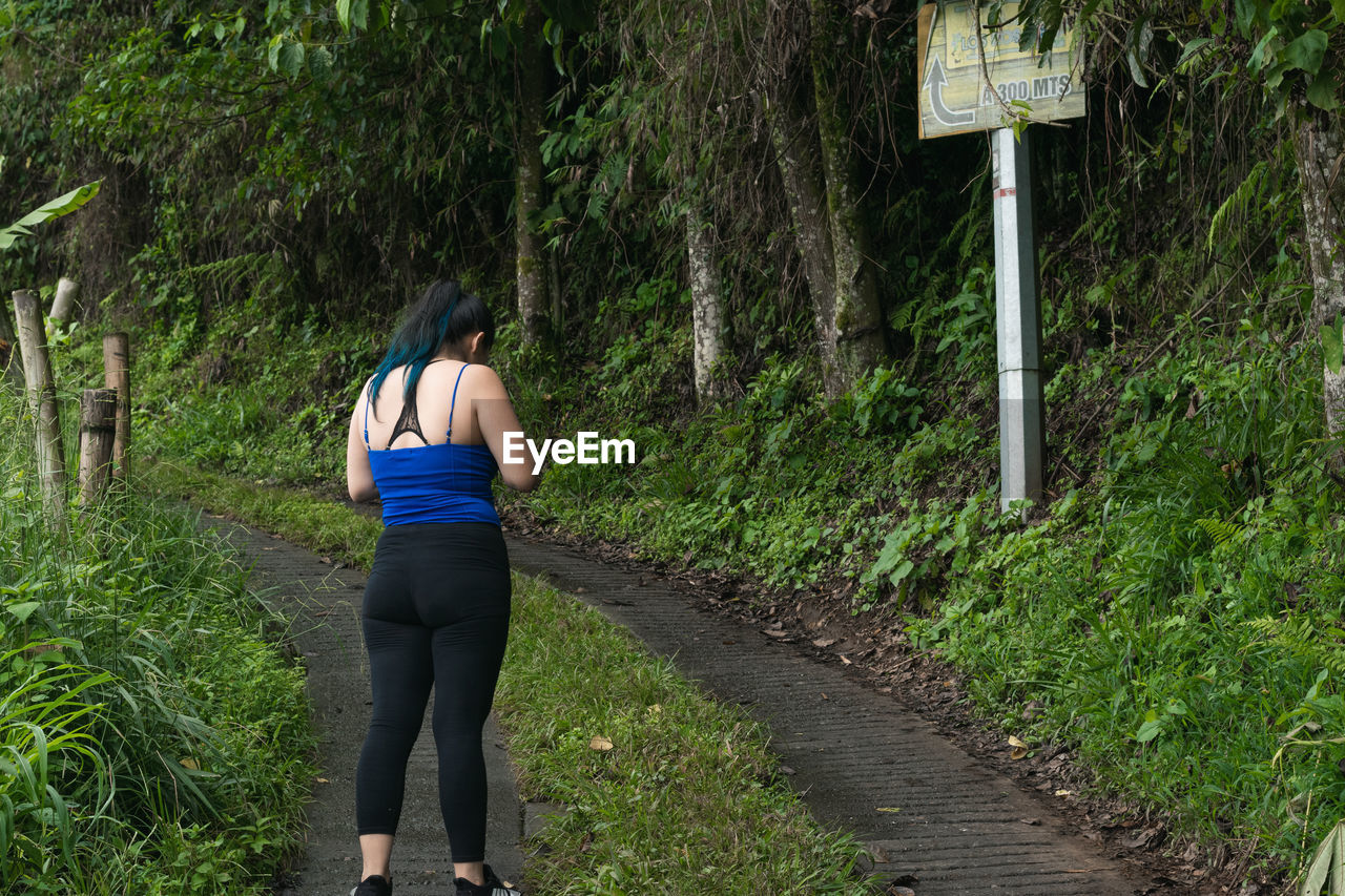 one person, plant, lifestyles, rear view, full length, green, women, nature, tree, adult, leisure activity, day, growth, trail, casual clothing, sports clothing, land, footpath, walking, outdoors, clothing, forest, exercising, sports, person, road, young adult, standing, grass, running