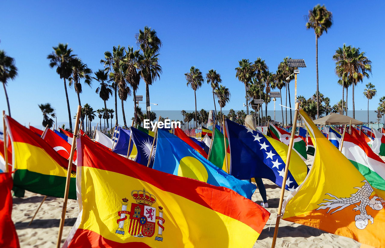 Multi colored flags at beach against sky