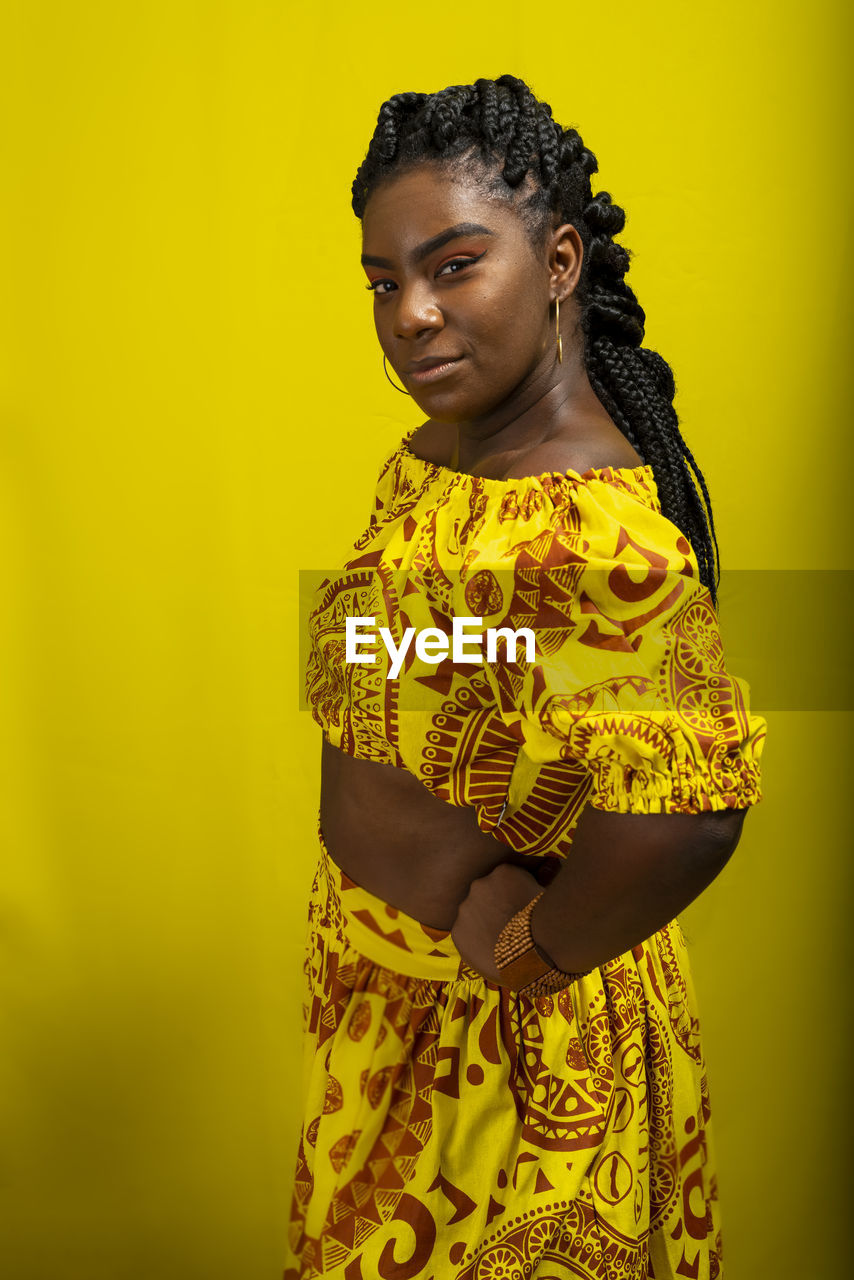 Young woman wearing colorful long clothes over yellow background. natural expression.