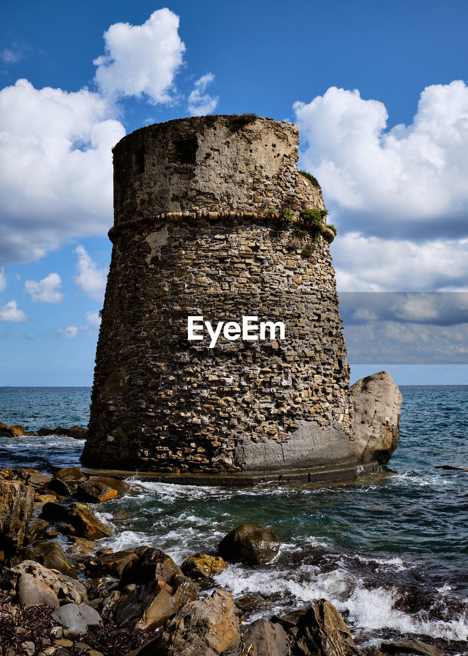 Rock formation on sea shore against sky