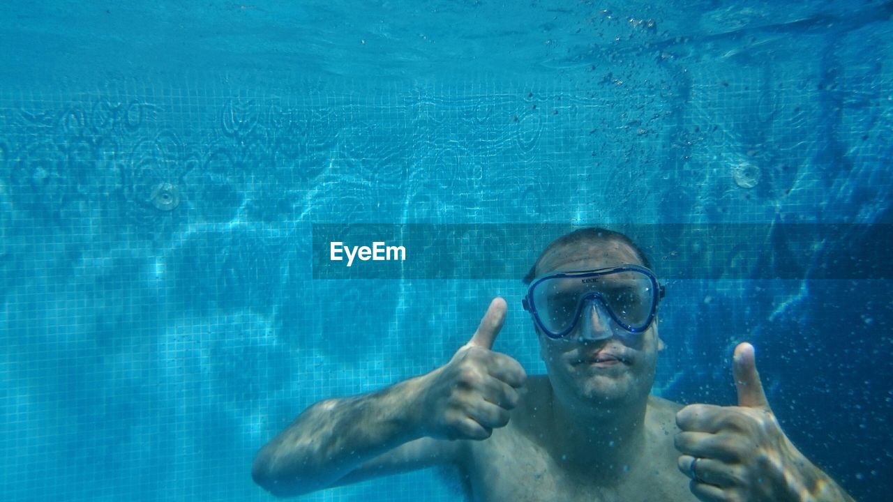 Man swimming while gesturing thumbs up sign in sea