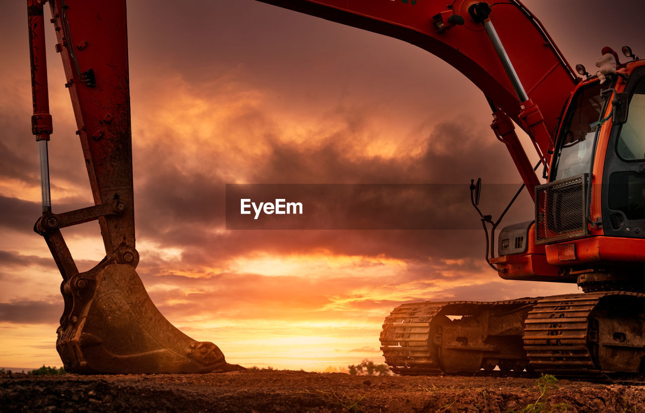 Backhoe parked at construction site after digging soil. bulldozer on sunset sky and clouds.