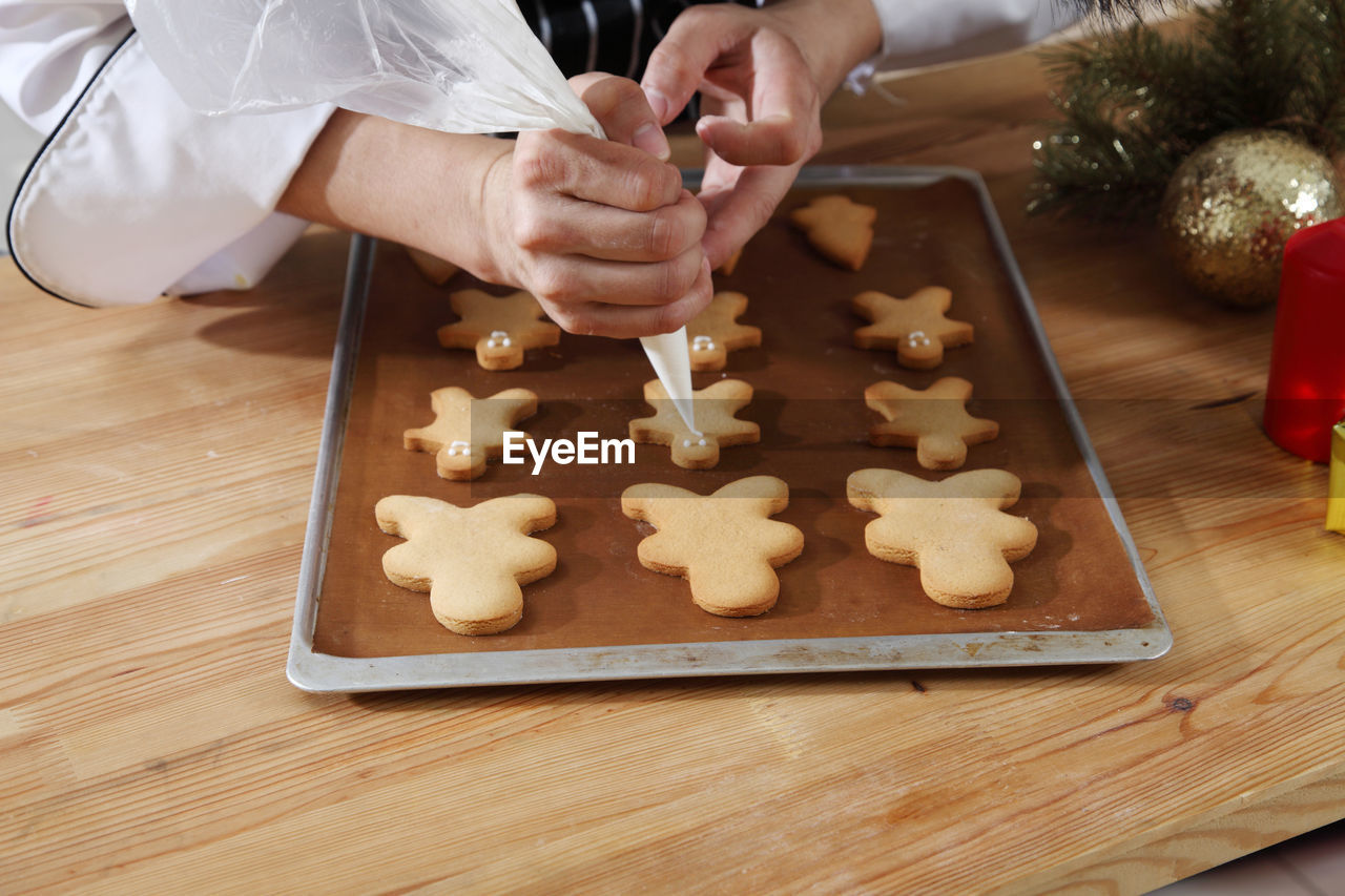 Midsection of chef preparing gingerbread cookies on table