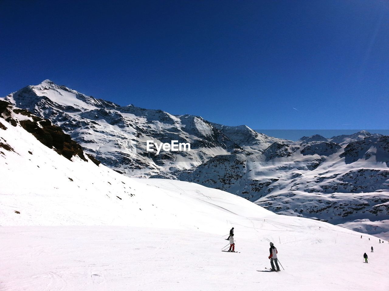 People skiing on snow covered landscape against clear sky