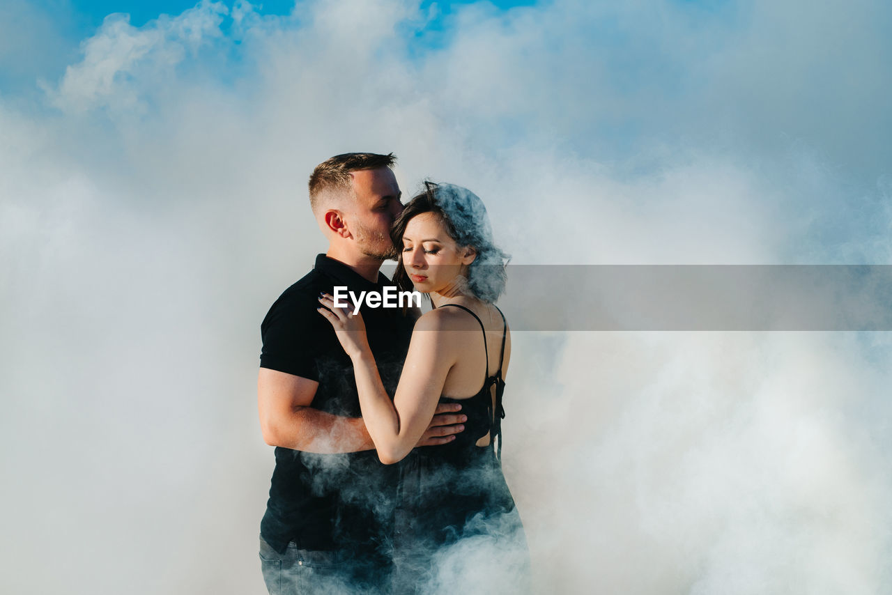 YOUNG COUPLE ON ROCK AGAINST SKY