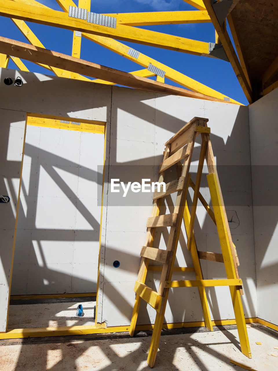 Low angle view of ladder against yellow wall