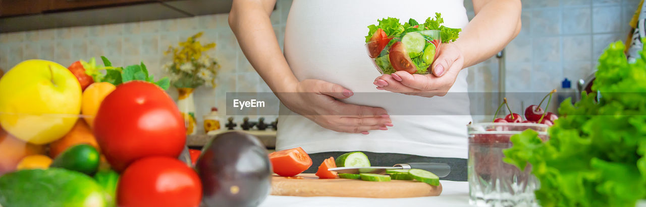 Midsection of pregnant woman holding salad bowl