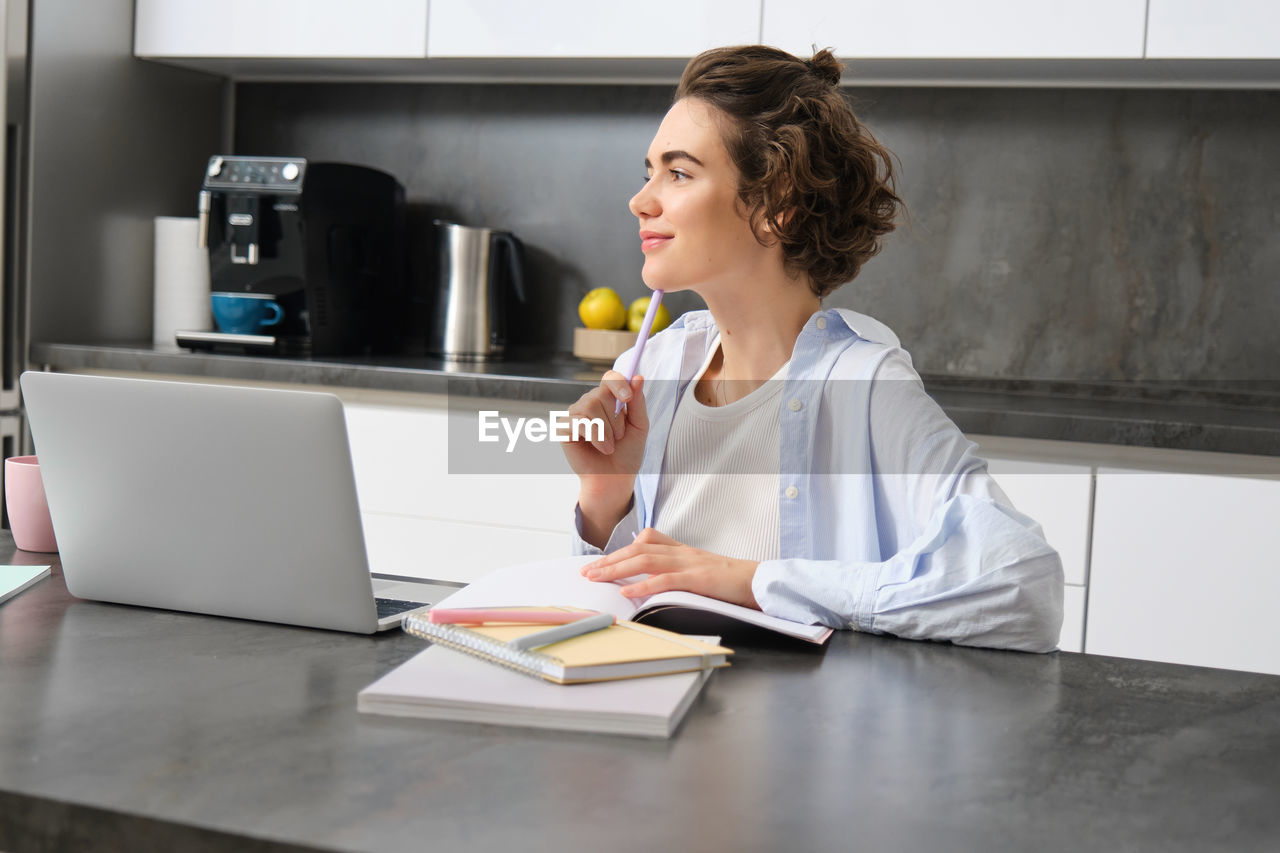 portrait of young woman using laptop at desk in office