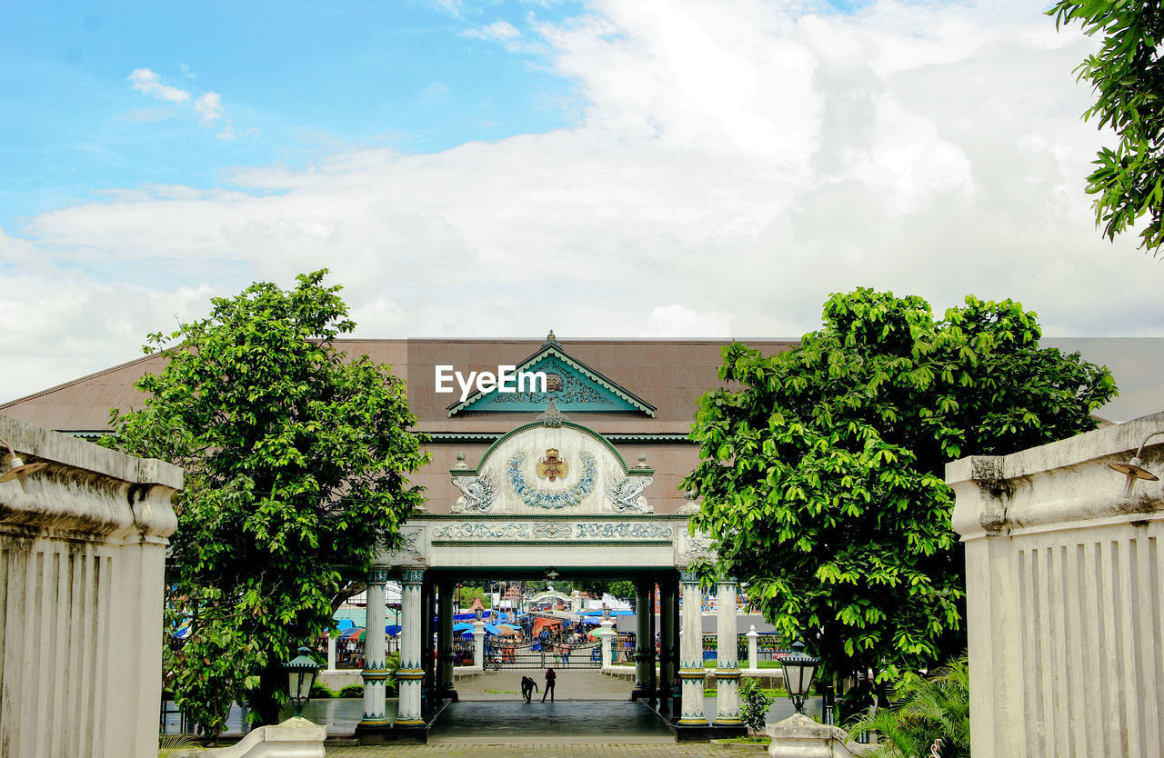 architecture, built structure, building exterior, plant, tree, cloud, estate, sky, building, nature, neighbourhood, entrance, gate, home, day, house, outdoors, residential area, city, facade, town, travel destinations, religion, adult, the past, residential district, history