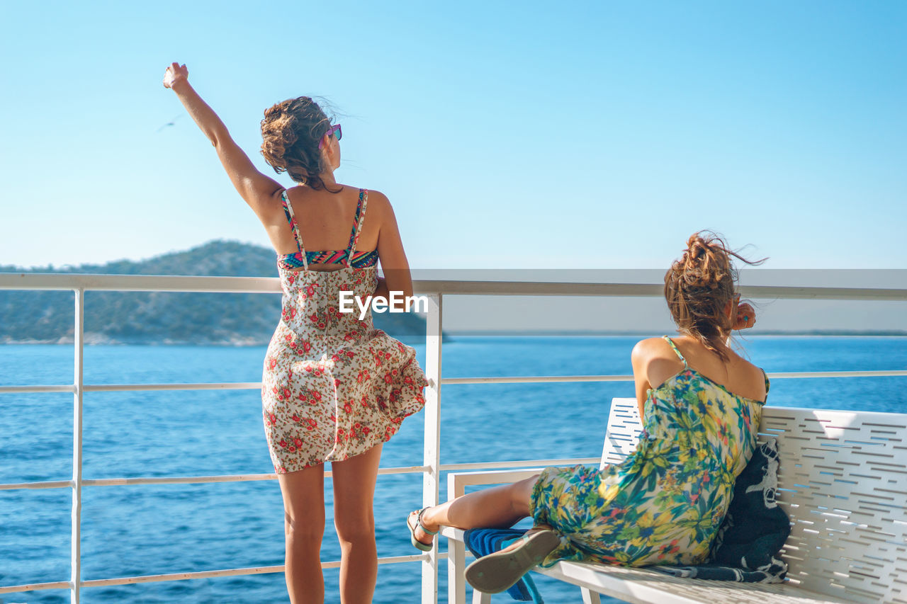 Young women spending leisure time on boat deck against sky