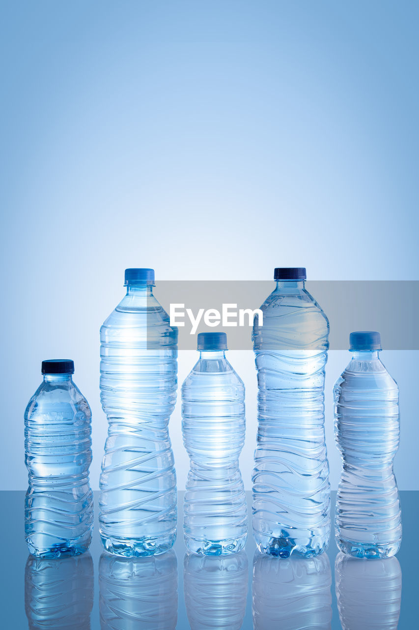 Collection of water bottles isolated on blue background with copy space. vertical format.