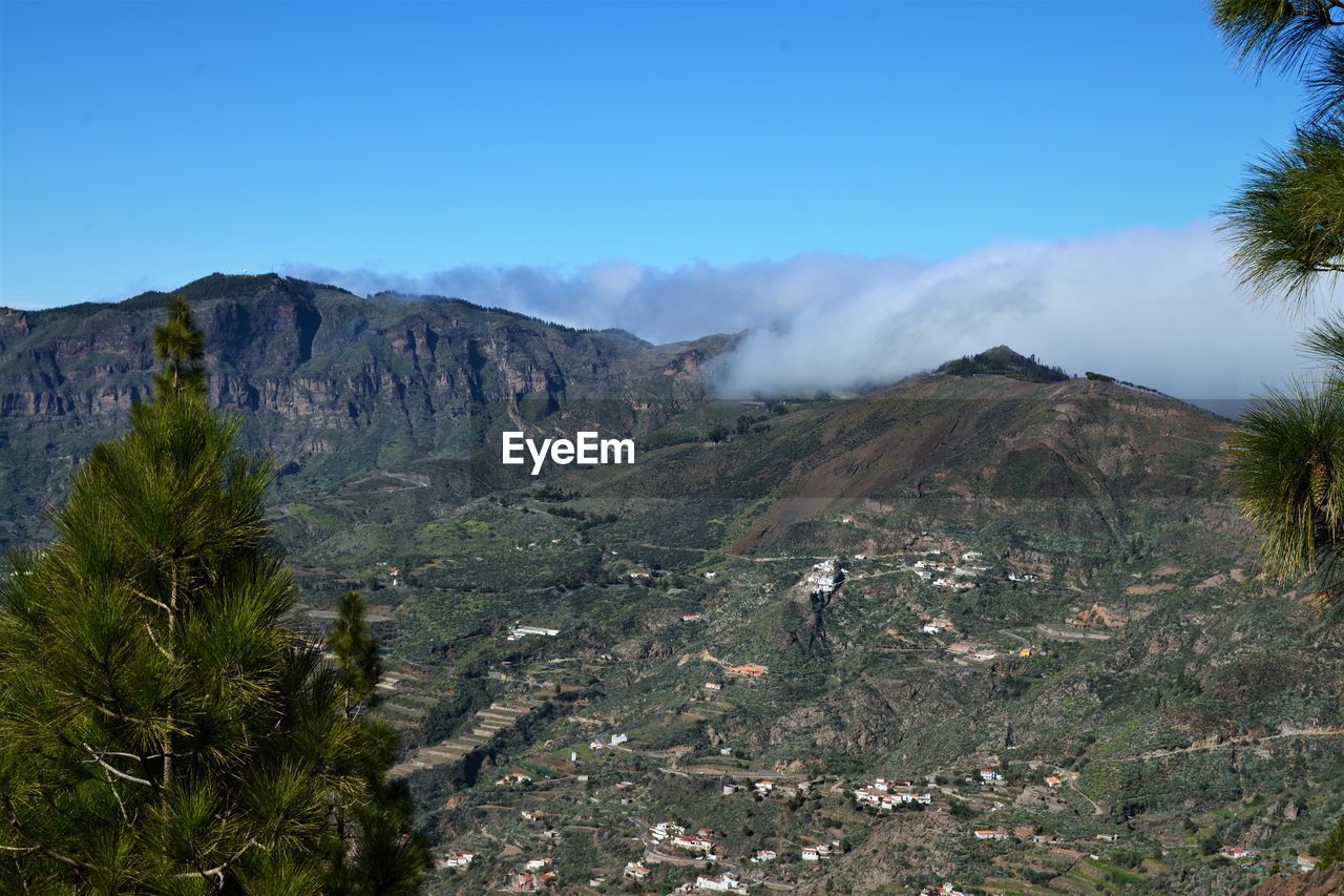 Scenic view of landscape and mountains against blue sky