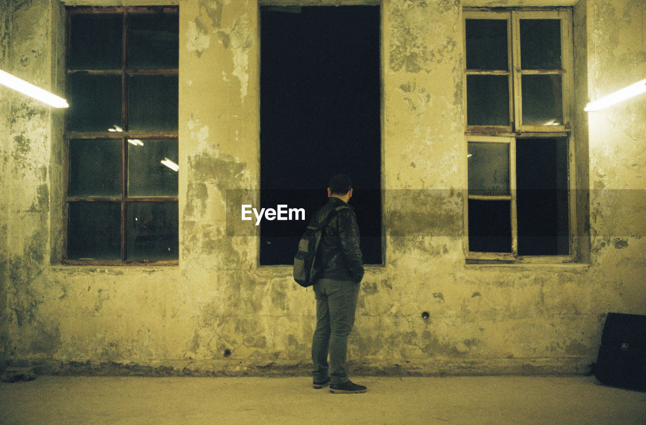 Side view of man standing in illuminated abandoned building