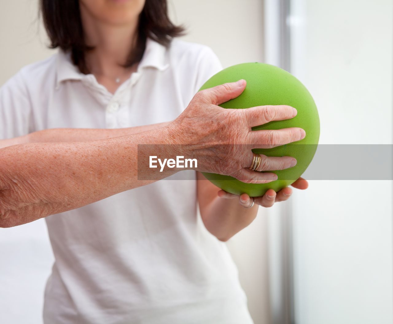 Close-up of women hands holding green ball in gym