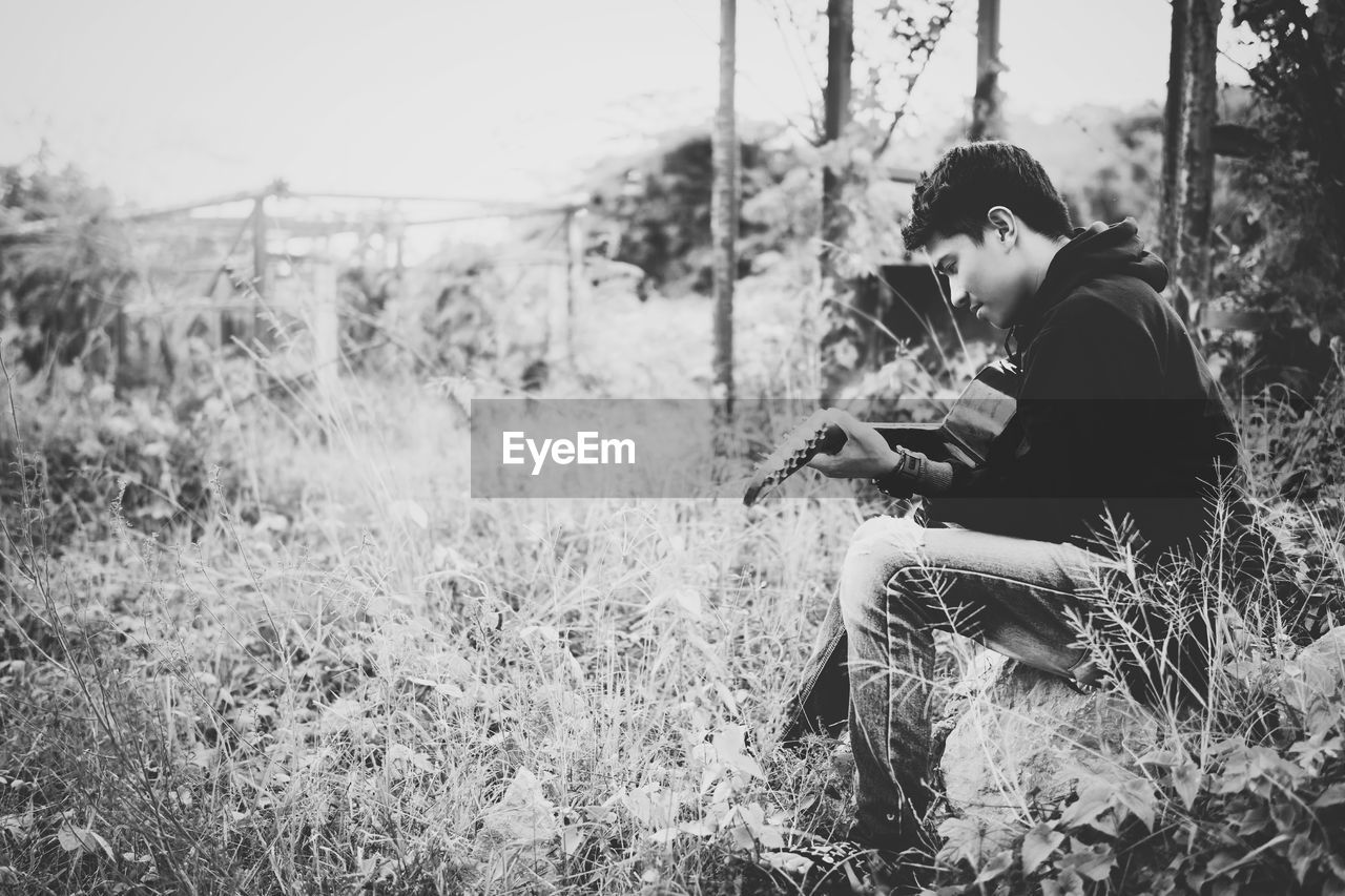 Man playing guitar on grassy field