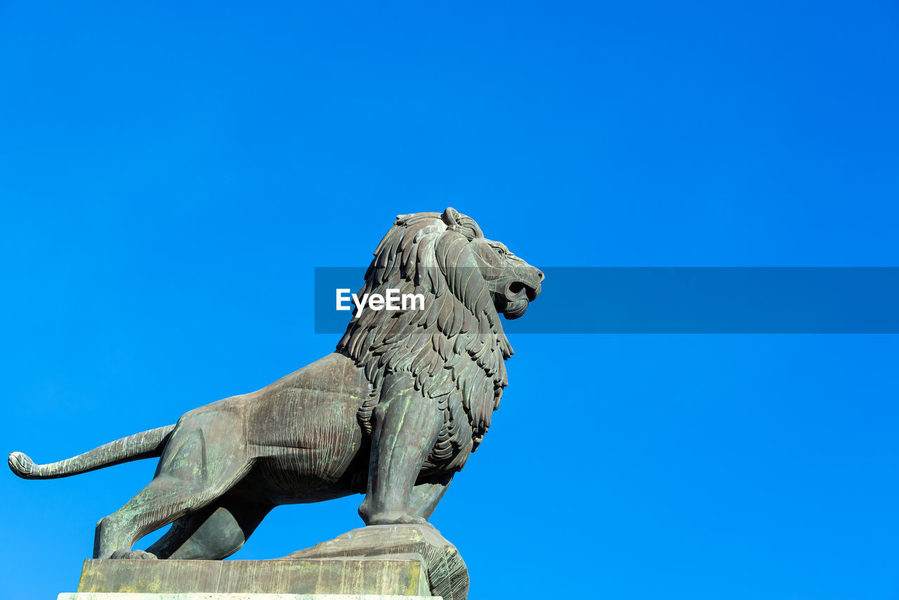 LOW ANGLE VIEW OF BIRD STATUE AGAINST BLUE SKY