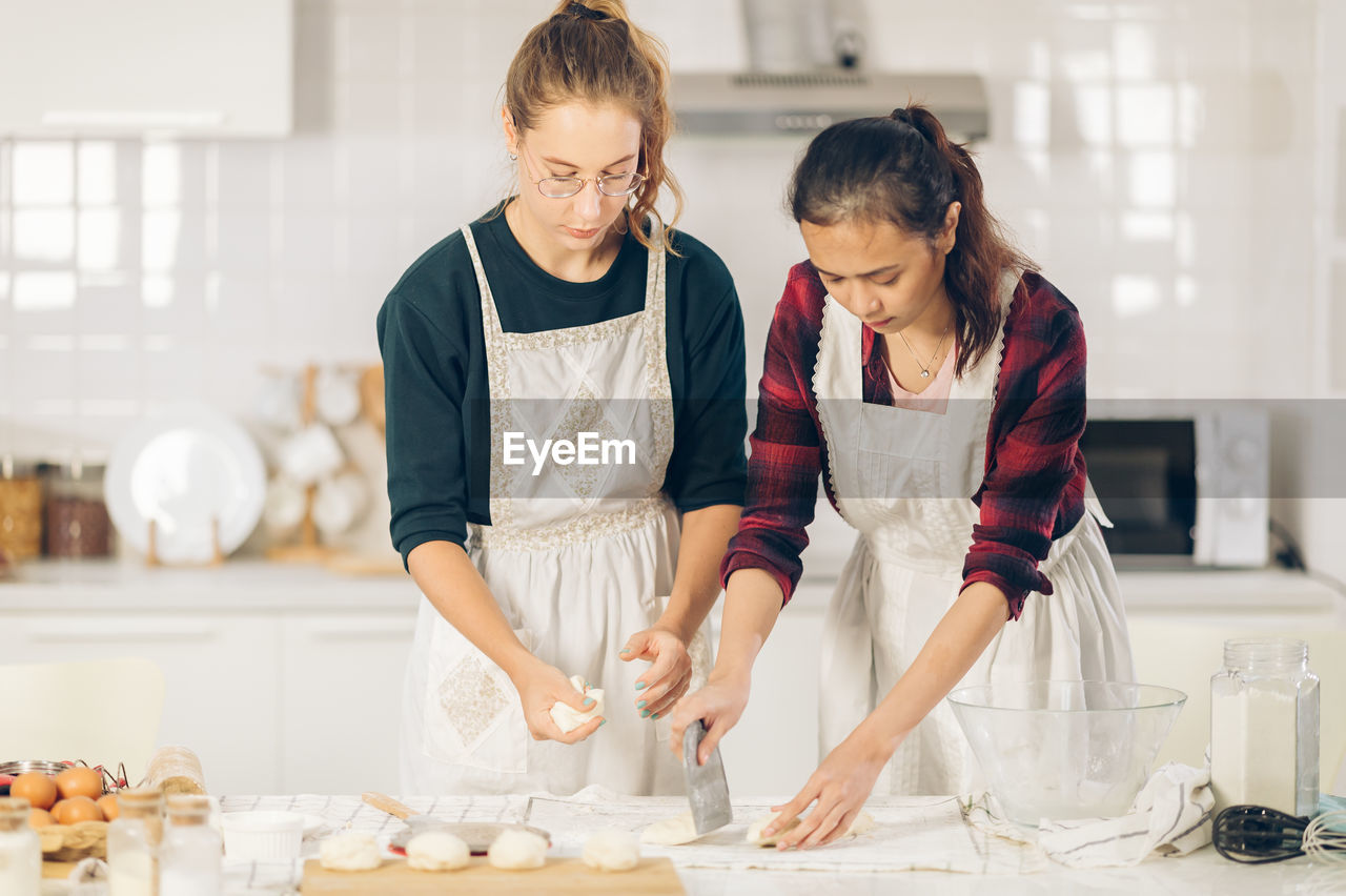 Female hands kneading dough in kitchen