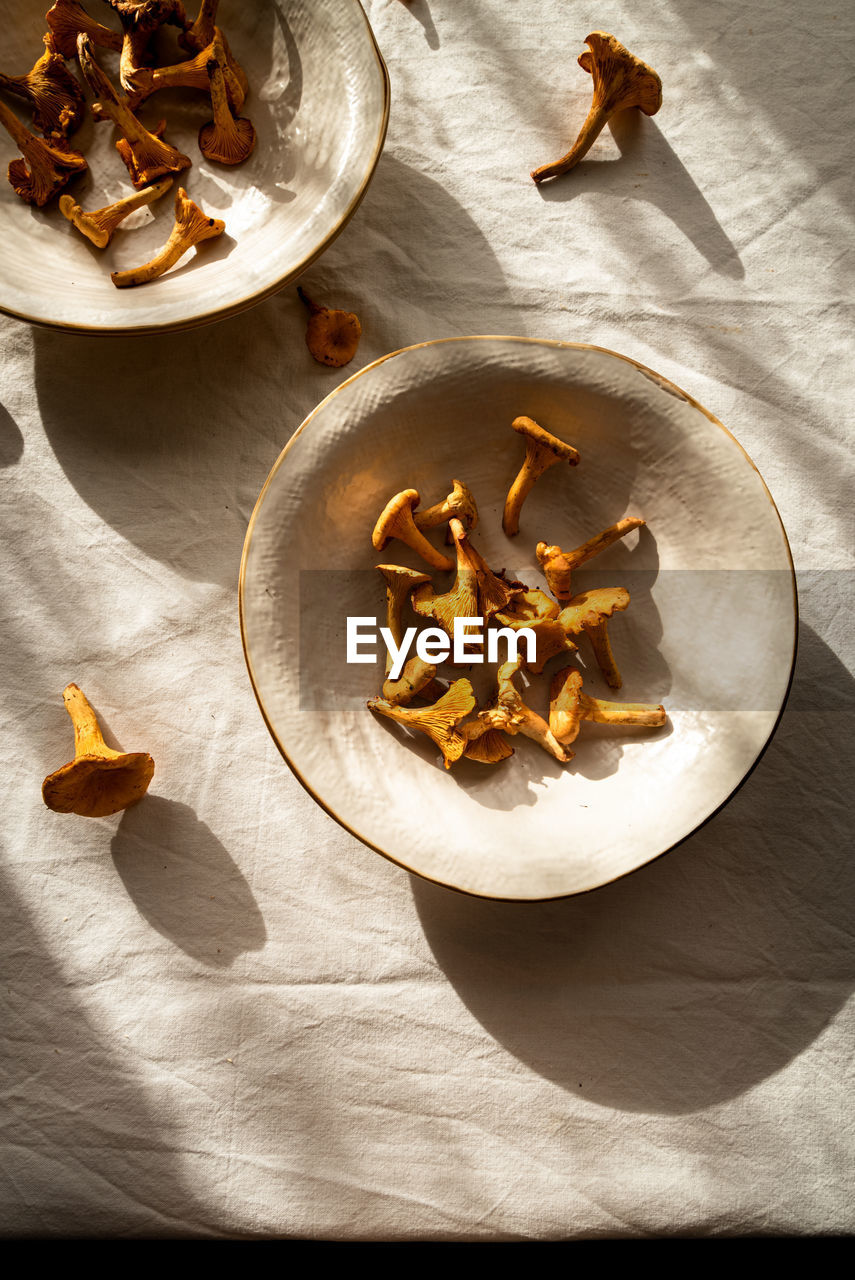 High angle of chanterelle mushroom on bowl placed on table at sunlight in countryside home