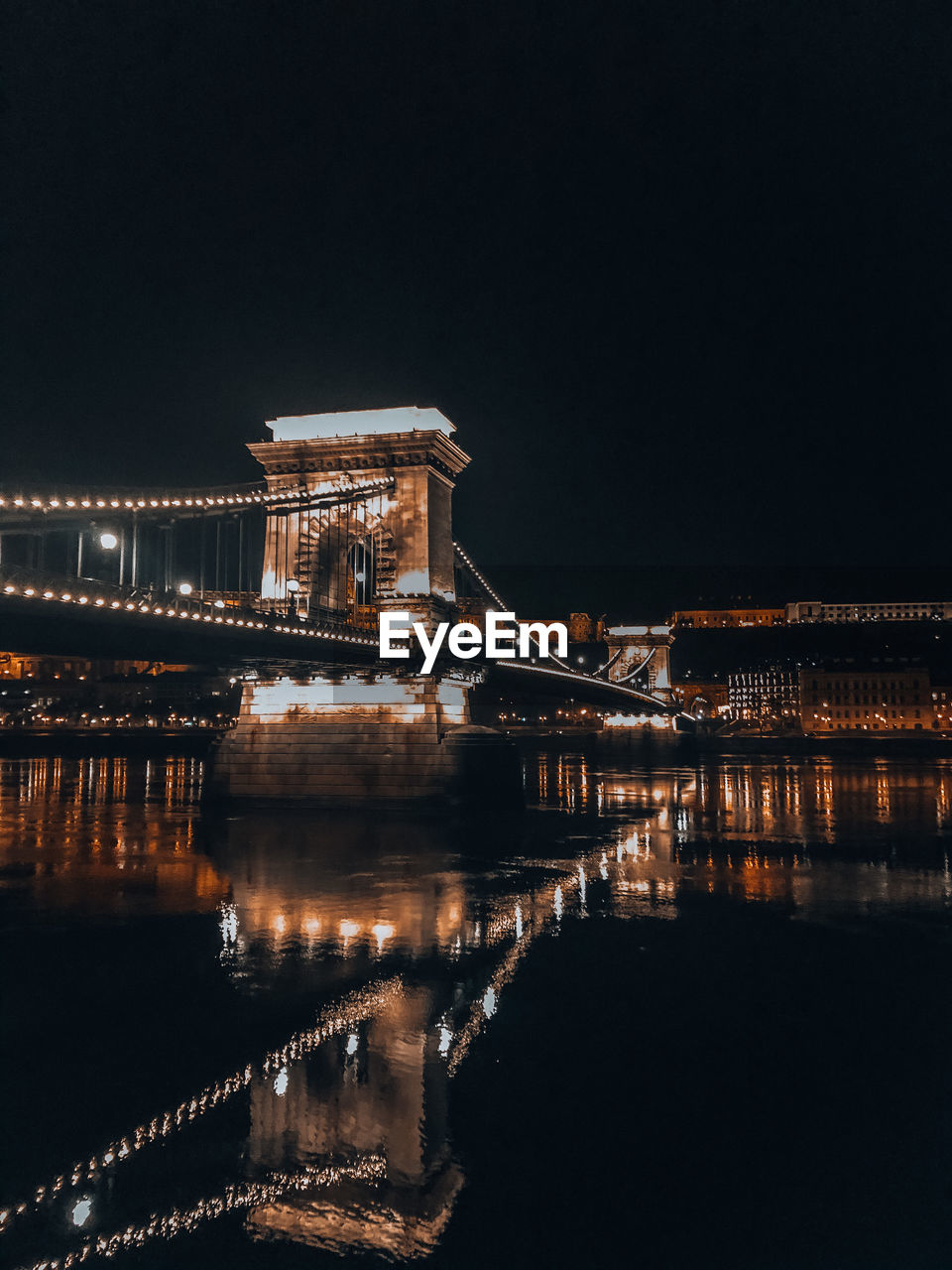 Illuminated bridge over river against sky at night