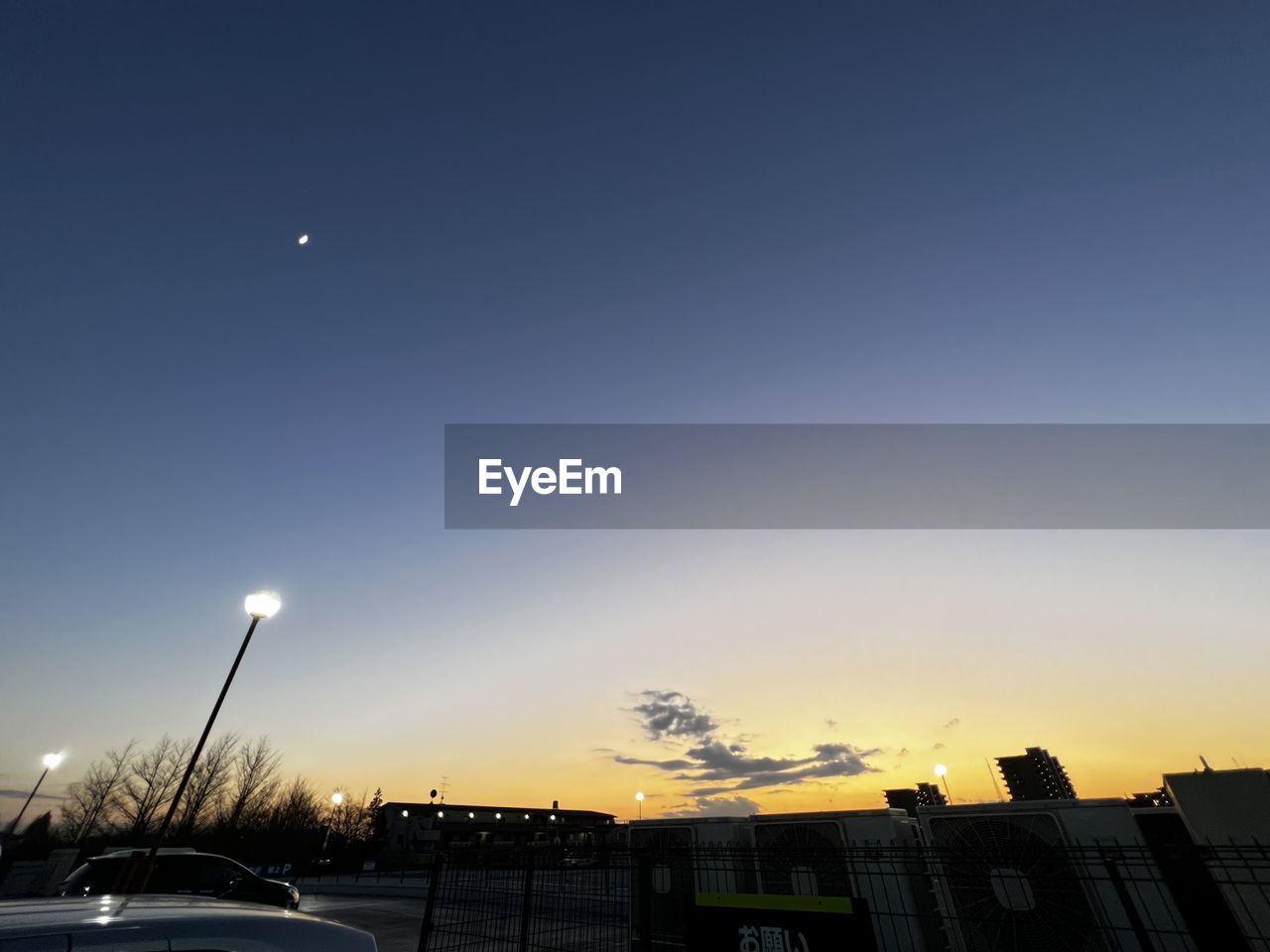 sky, car, transportation, mode of transportation, motor vehicle, evening, architecture, dusk, moon, built structure, city, nature, building exterior, night, no people, horizon, land vehicle, sunset, light, vehicle, street, astronomical object, cloud, street light, outdoors, road