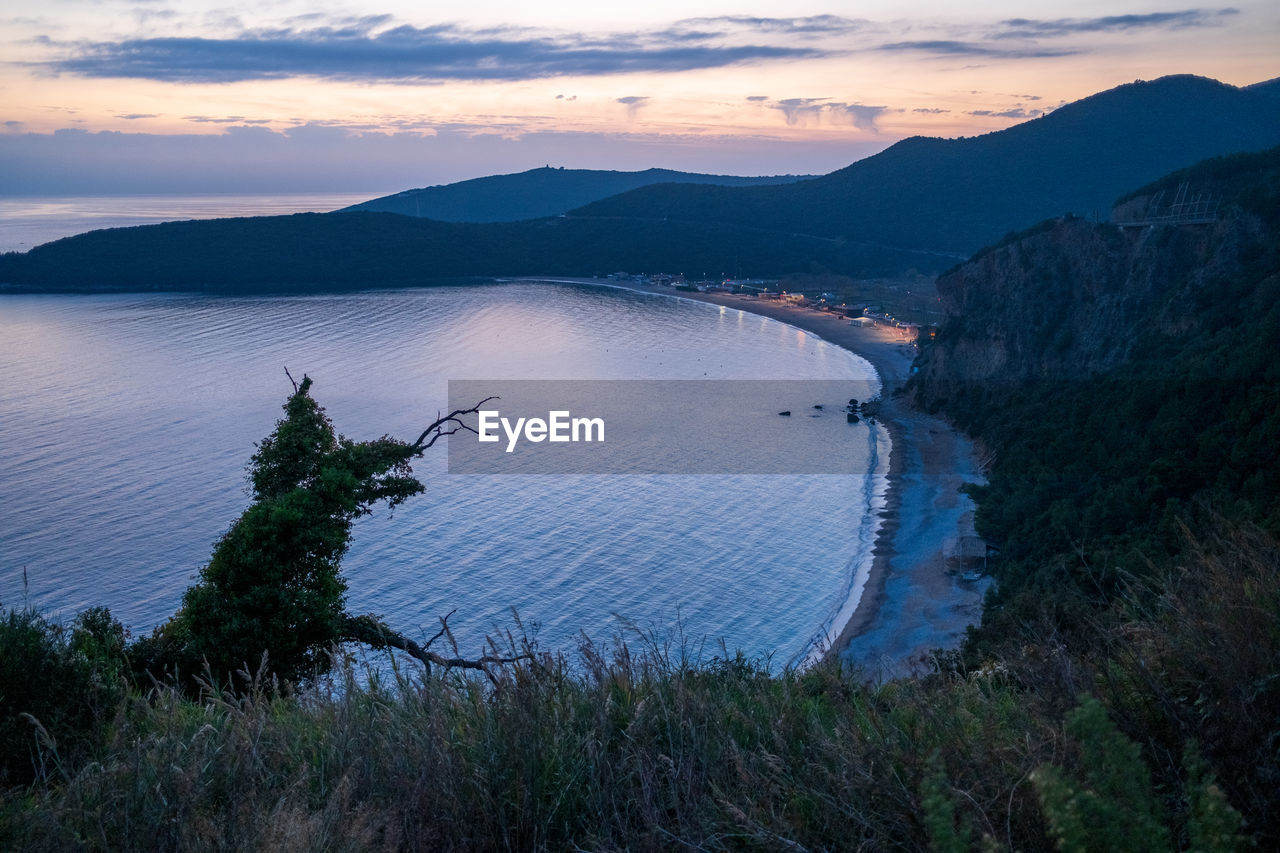 high angle view of townscape by lake against sky during sunset