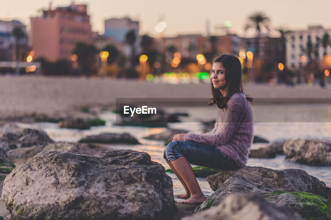 Portrait of young woman sitting on rock