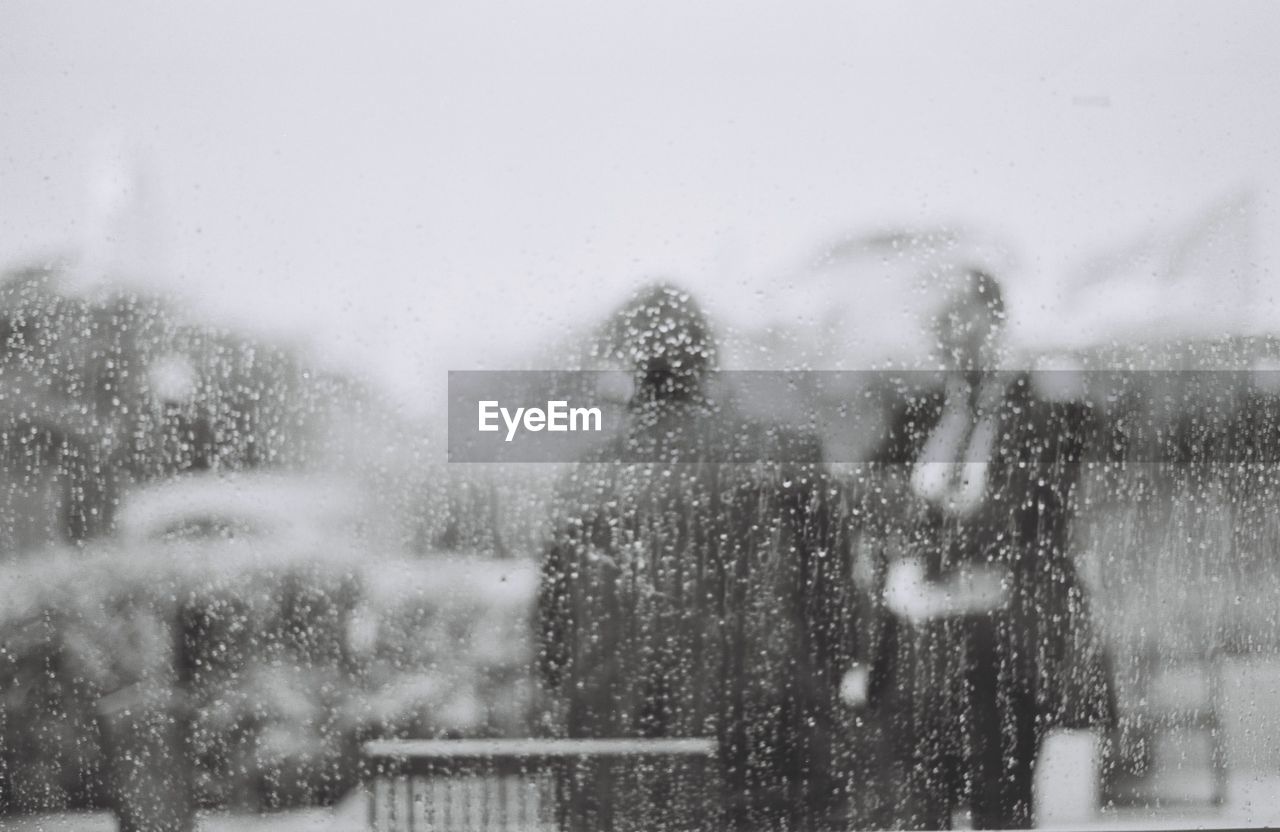 People seen through glass window on rainy day