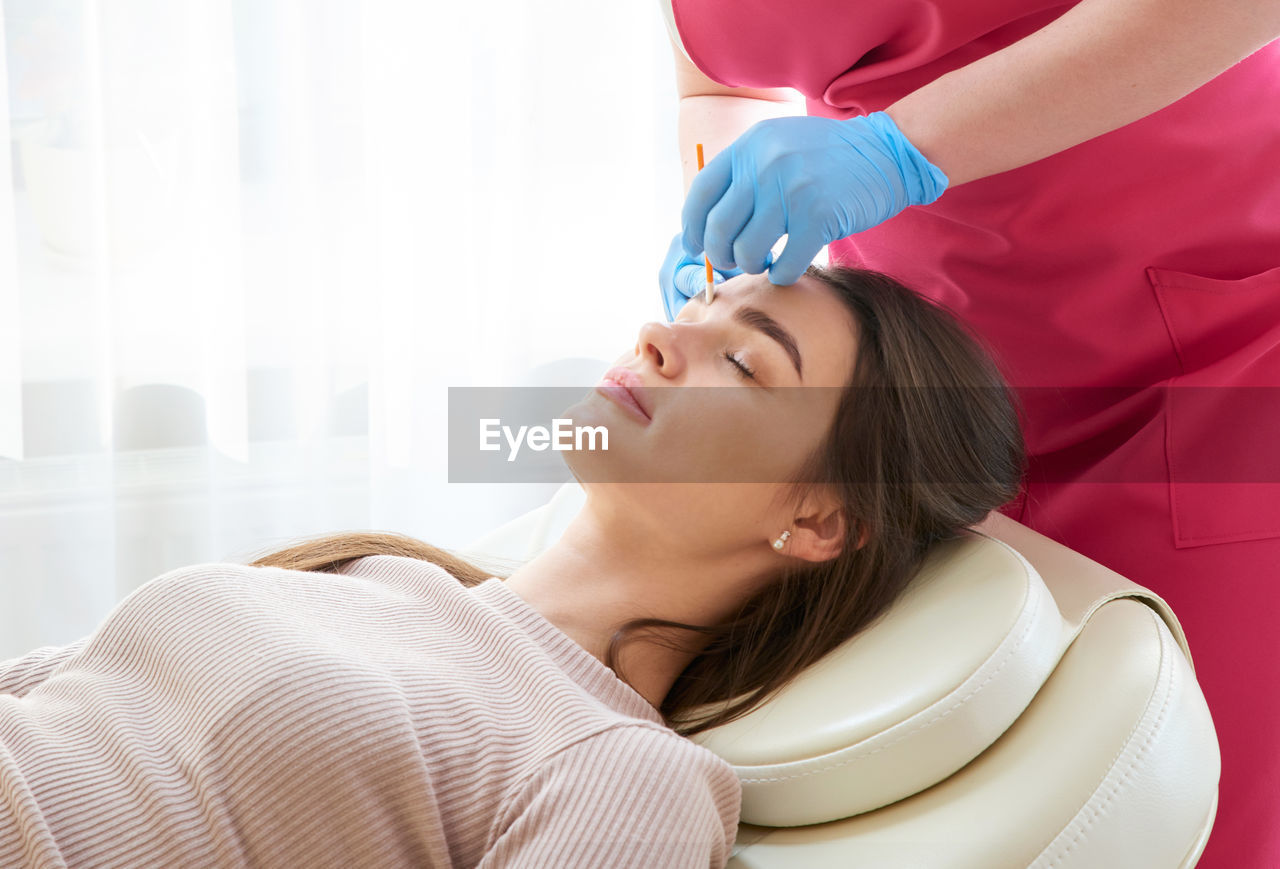 Woman getting eyebrows done in beauty spa