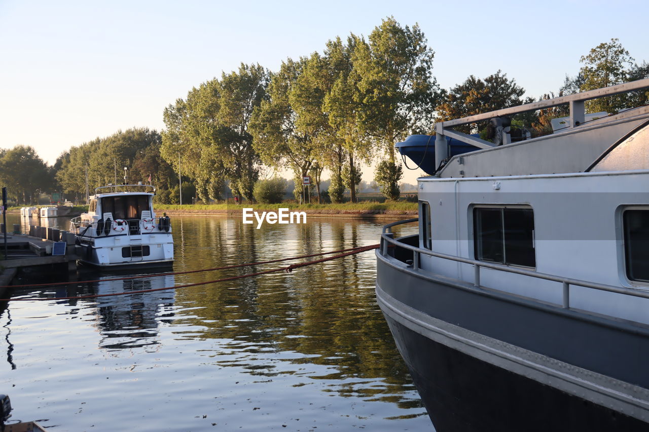 water, transportation, nautical vessel, tree, mode of transportation, boat, vehicle, waterway, nature, sky, lake, plant, reflection, ship, dock, watercraft, architecture, day, clear sky, travel, no people, outdoors, holiday, house, vacation, boating, built structure, trip, moored, travel destinations