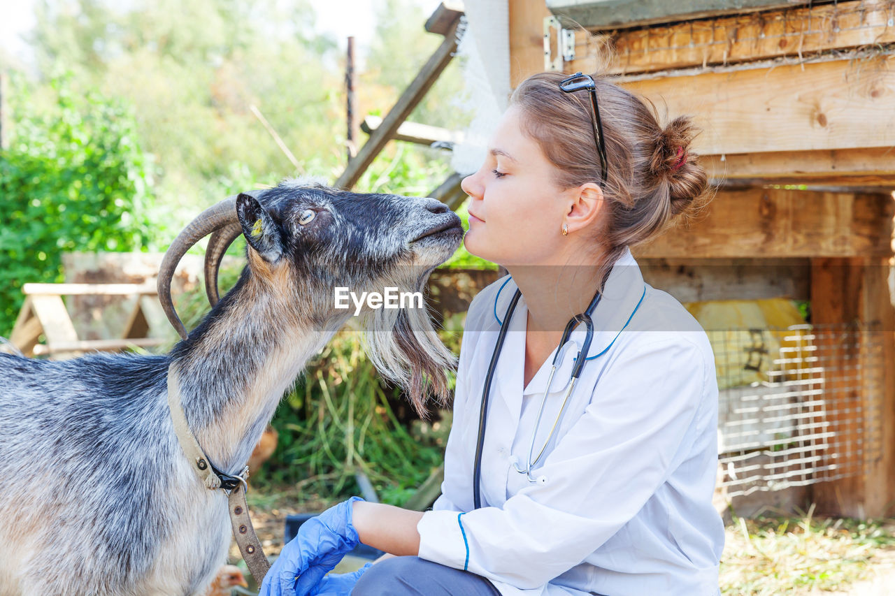 Veterinarian with goat outdoors
