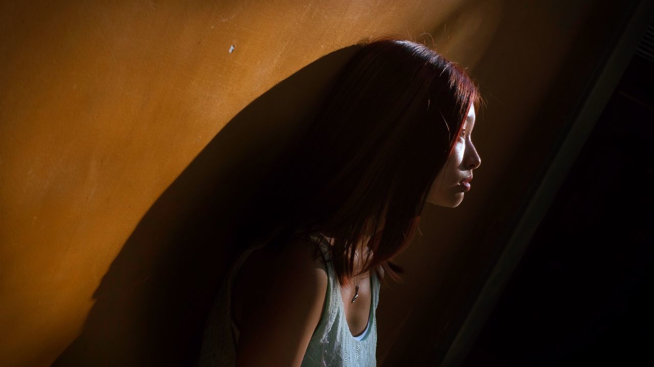 Side view of young woman standing by wall