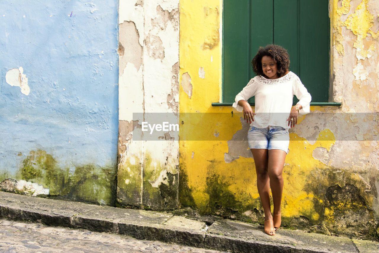 Model in a yellow dress smiling, looking and posing at the camera. 